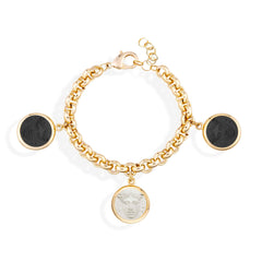 Gold chain bracelet with black and white disc charms on a white background